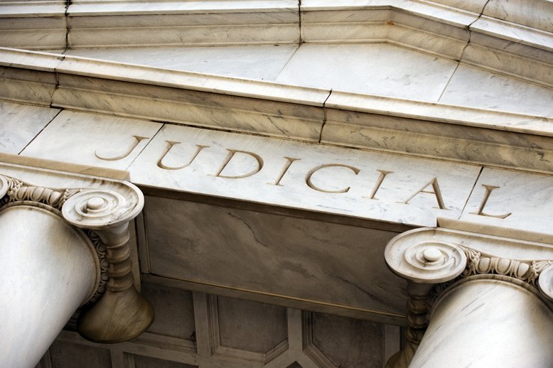 Photo of courthouse building with "judicial" written on it [Image by creator Natalia Bratslavsky from AdobeStock]